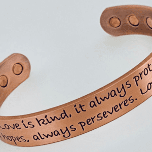 A copper bracelet with the words love is kind, it always protects.