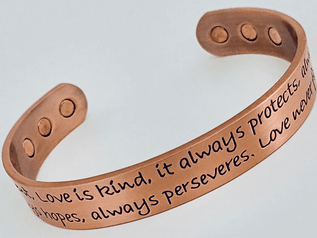 A copper bracelet with the words love is kind, it always protects.